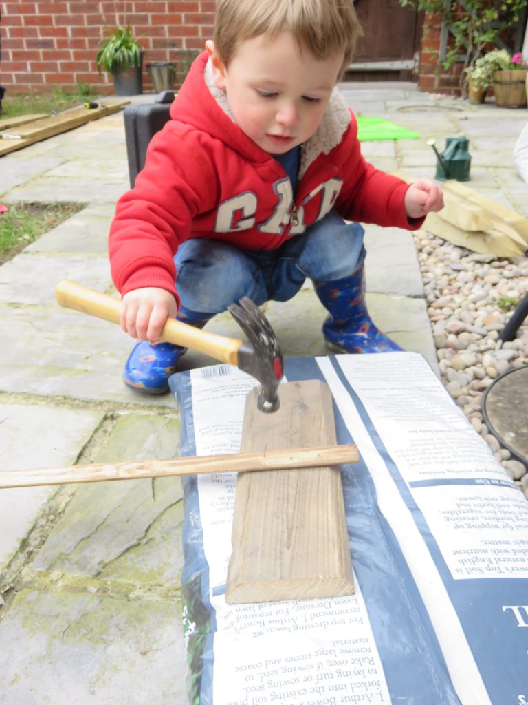 child hammering a sign in the garden