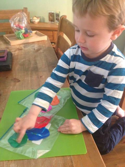 child pressing down on paint in a freezer bag