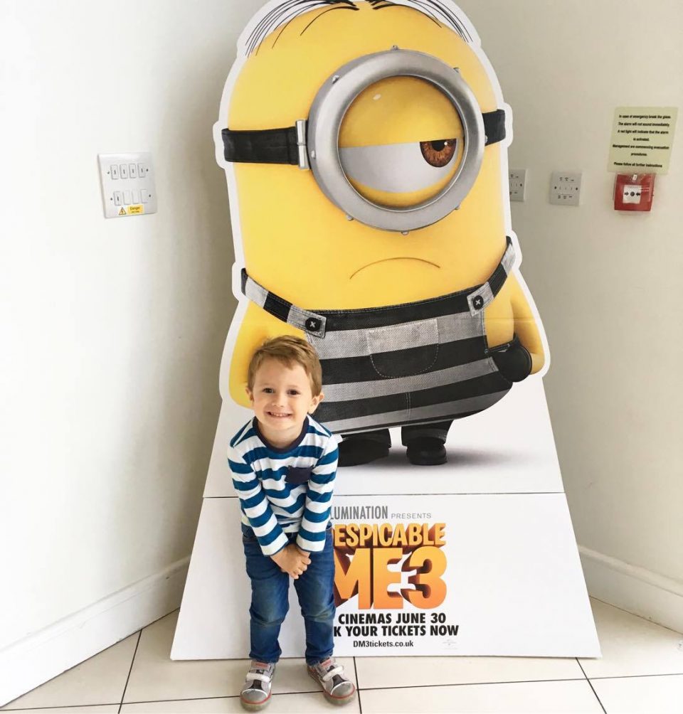 child in front of minions cardboard cut out
