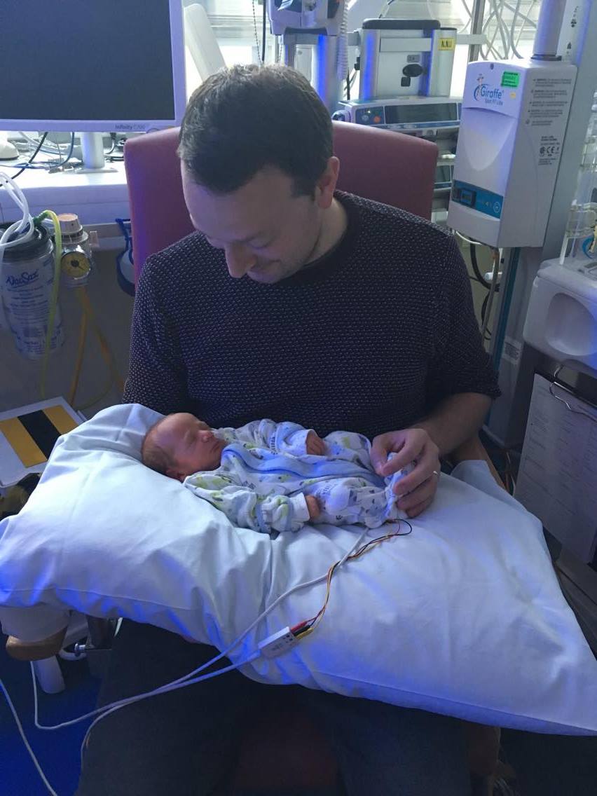 Rob holding William in NICU on a pillow for comfort