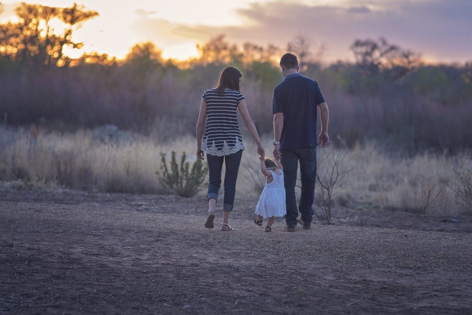 family of three walking in a field