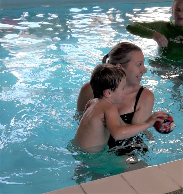 mum and child in pool. Child is holding a ball