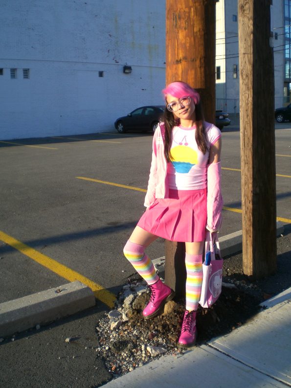 a lady stood next to a wooden pole wearing a lot of pink