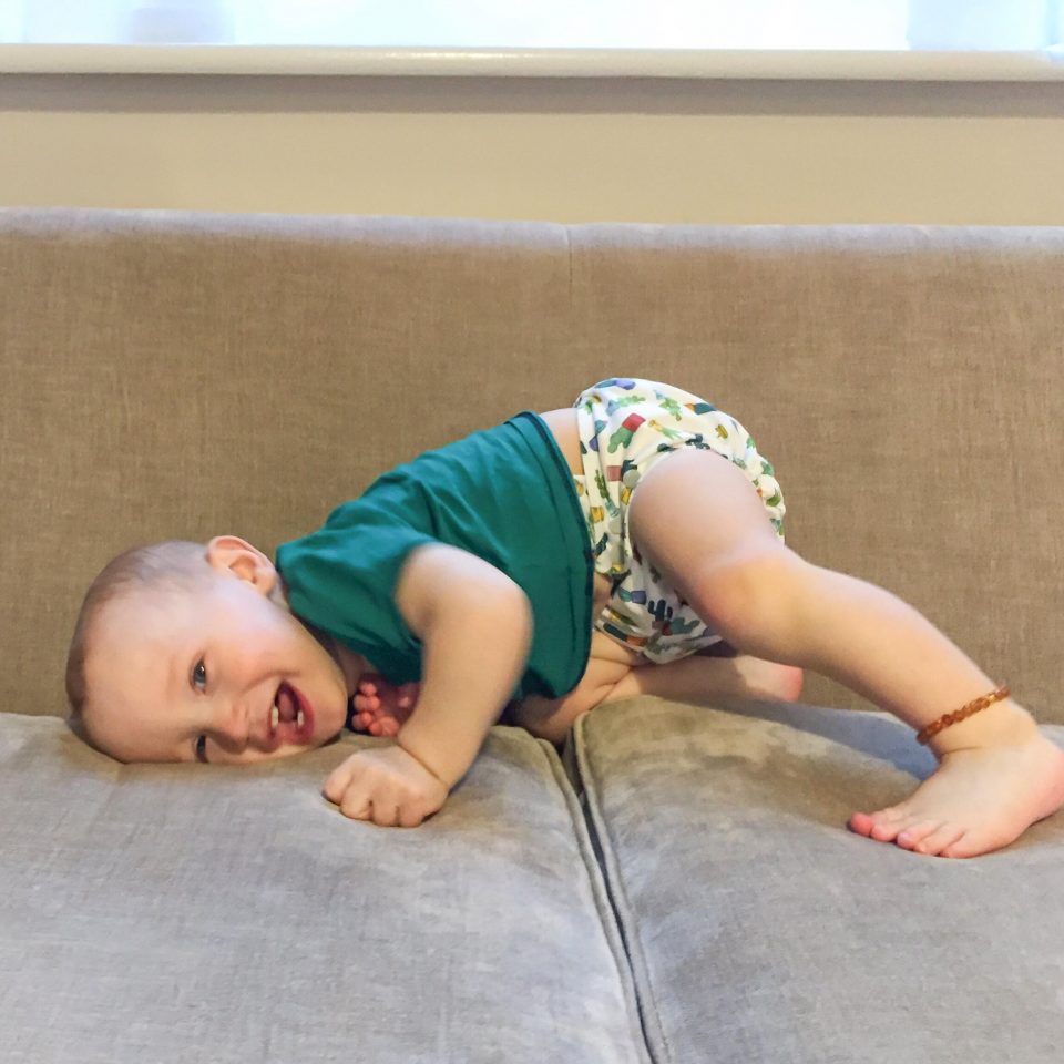 baby on sofa wearing an amber anklet