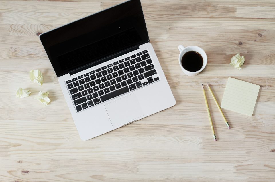 laptop, pencils, paper and coffee cup on a table