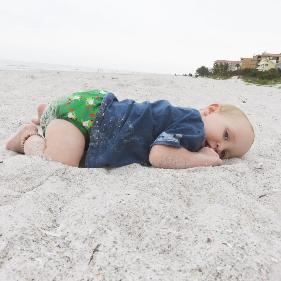 William laying on the beach in his cloth nappy