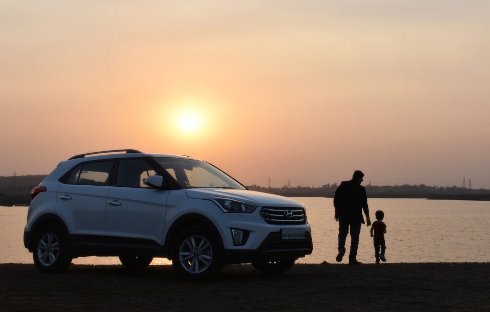 family car at sunset with a dad and child stood next to it