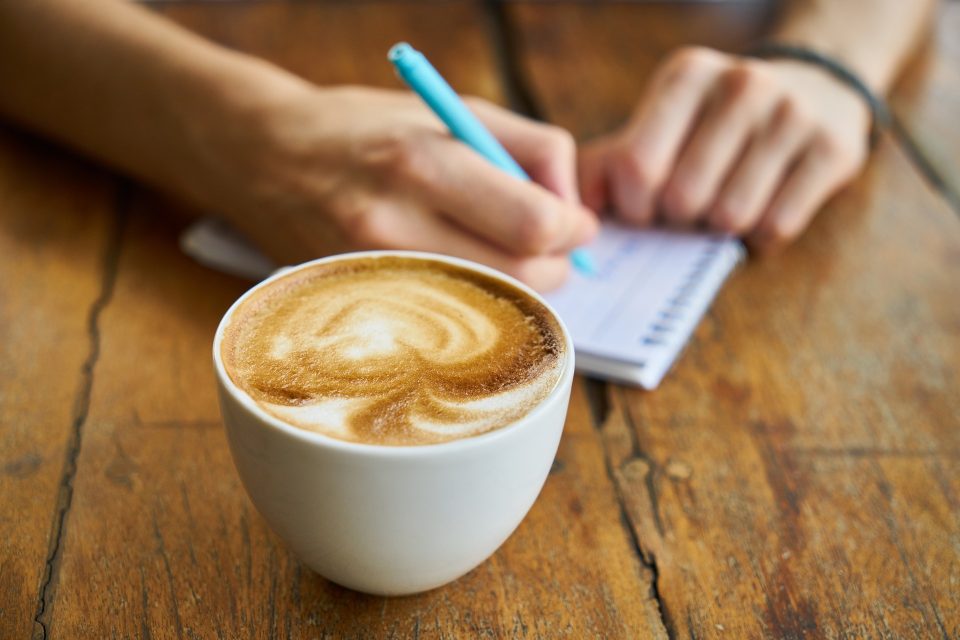 cup of coffee and someone writing a list