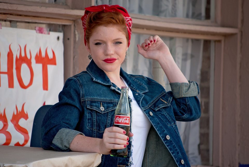 teenage girl in a denim jacket holding a bottle of coke