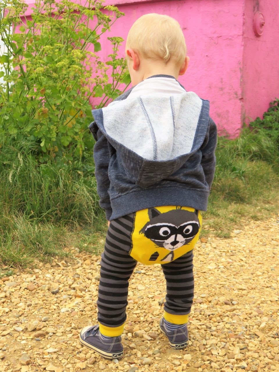 William with his back to us on a gravel path wearing his ricky raccoon leggings