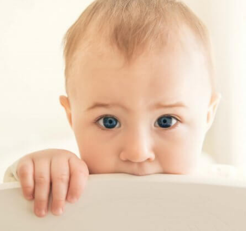 teething baby chewing its cot