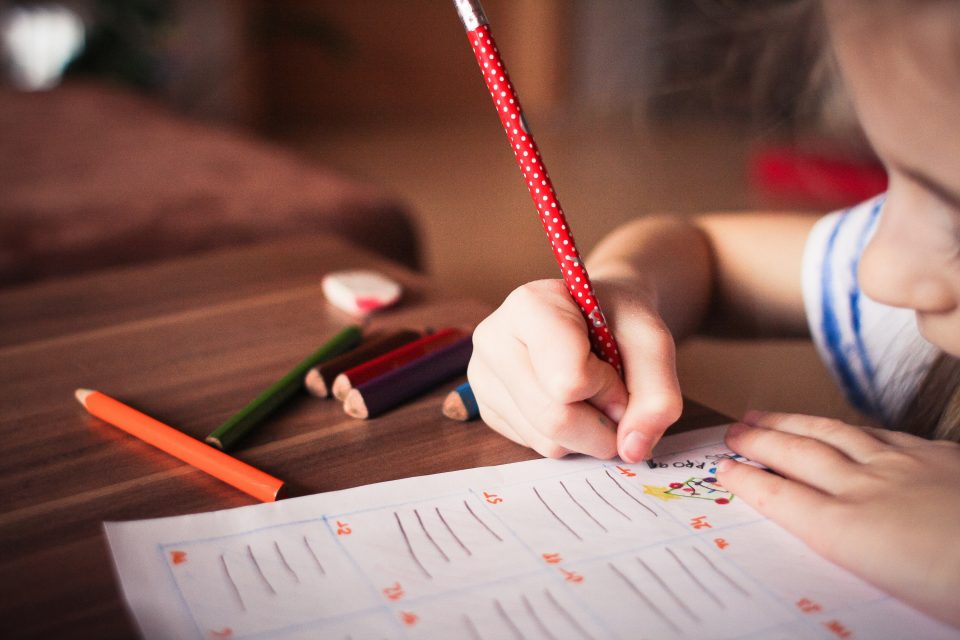 child holding a pen and writing