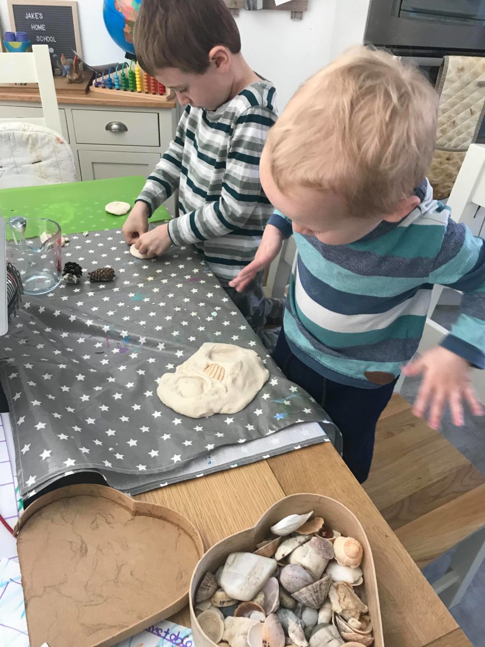 the boys making impressions in their salt dough dinosaur fossils