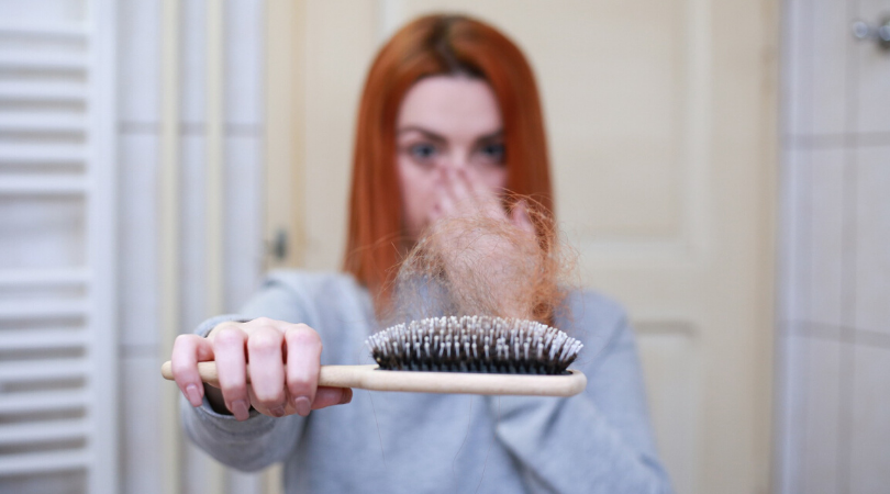 lady holding out a brush with hair on it