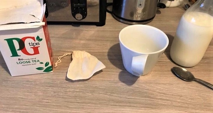 reusable tea bag next to a cup, the loose tea from Pg tips and a bottle of milk