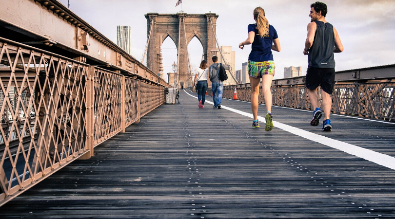 a couple running together on a bridge