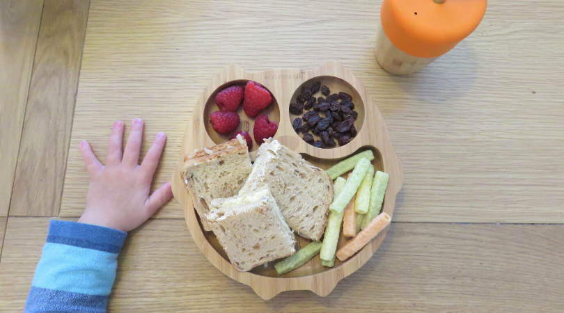 eco rascals bamboo owl plate and cup with a child's hand on the table