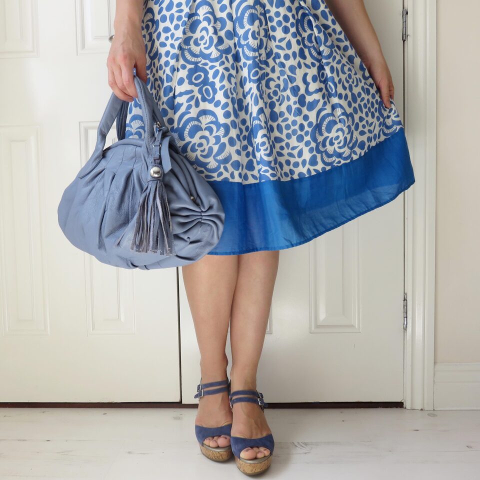 me wearing a blue flowery skirt with blue wedges and a blue handbag