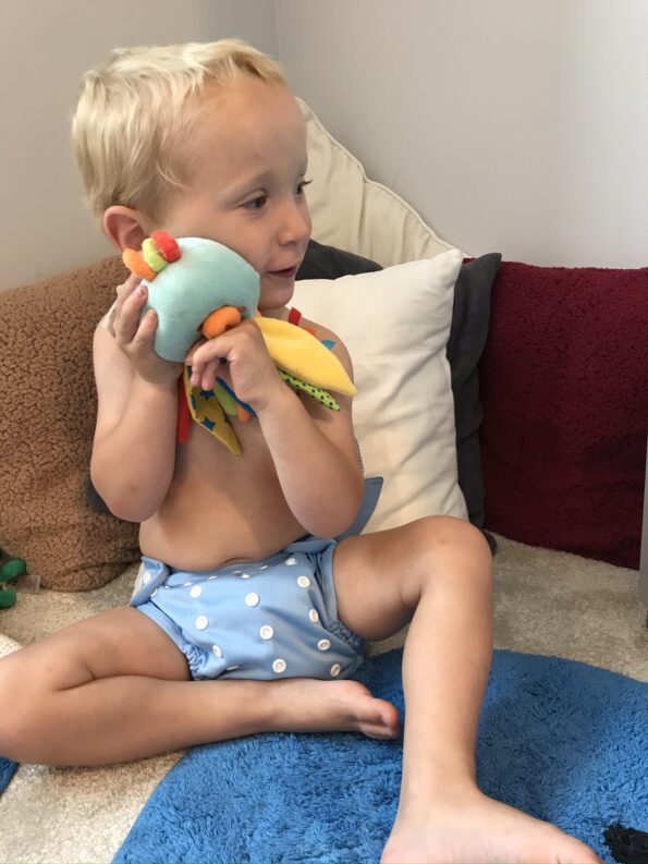 William cuddling a soft toy wearing his hippynut nappy