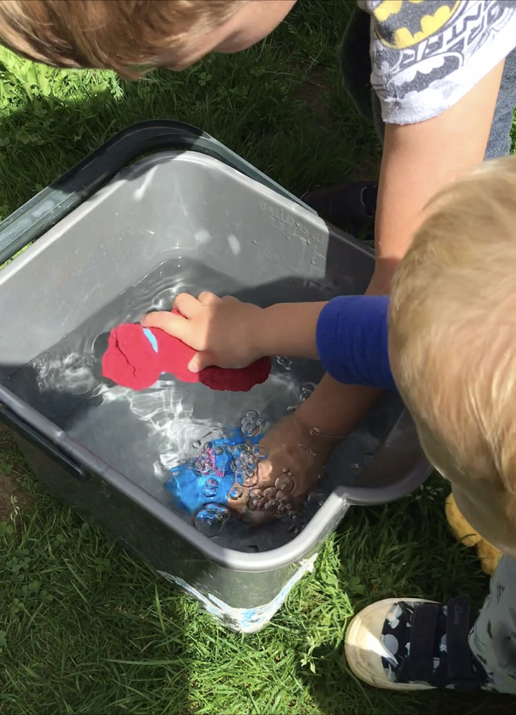 children dunking reusable water balloons into a grey bucket of water