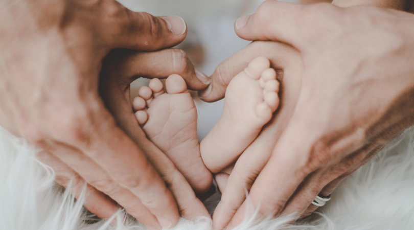 parent's hands around a baby's feet