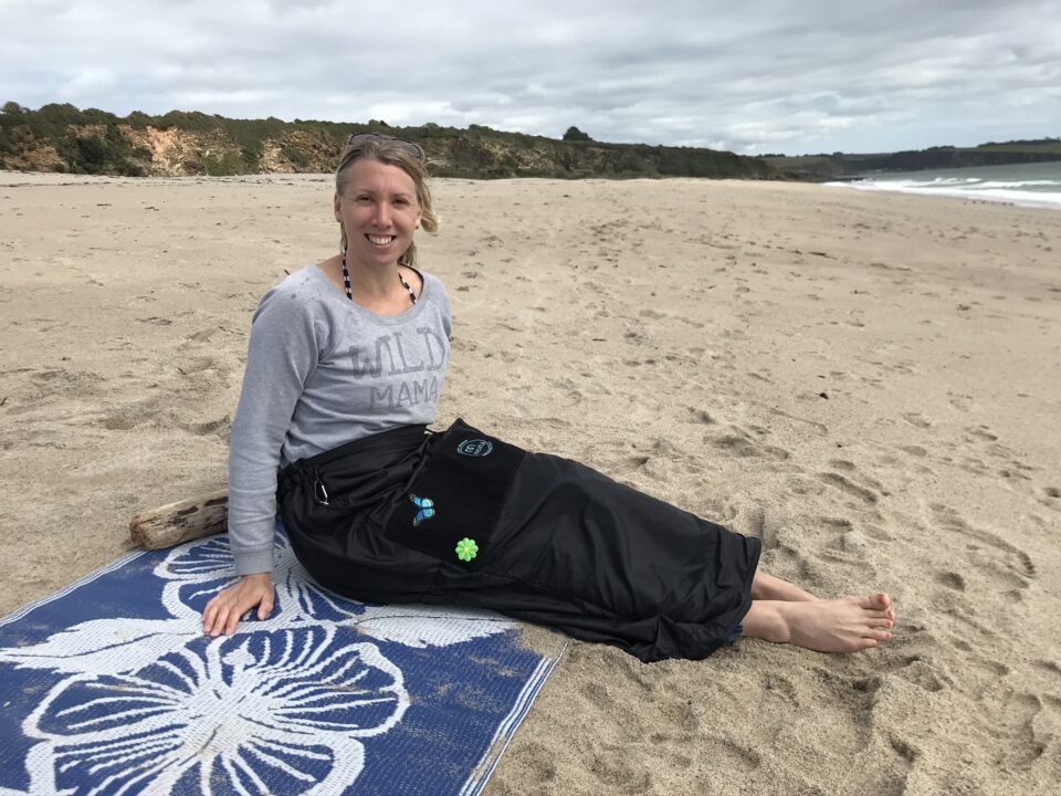 me sat on the beach wearing the mozy smiling at the camera