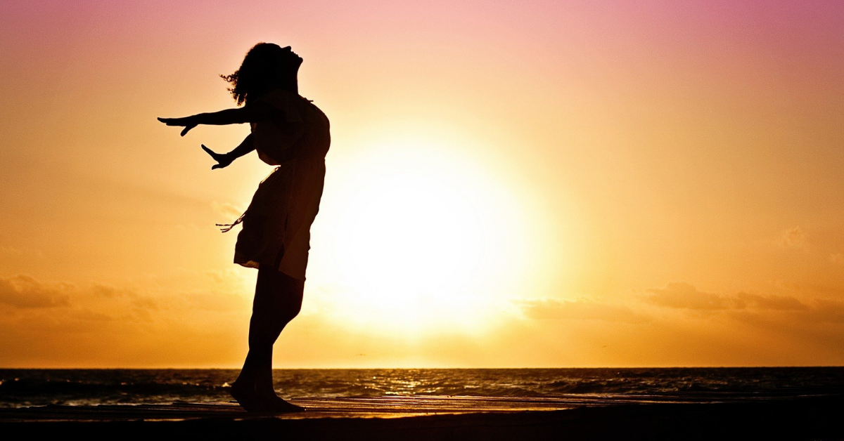 a lady at sunset holding her arms out