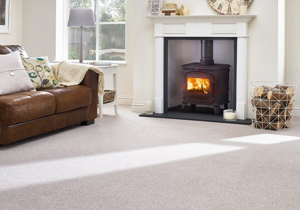 a light living room with cream carpet, log fire and sofa