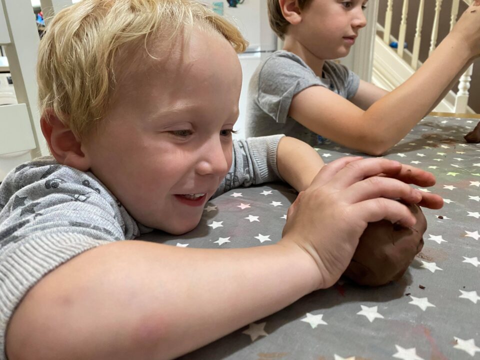 William smiling and making his clay hedgehog
