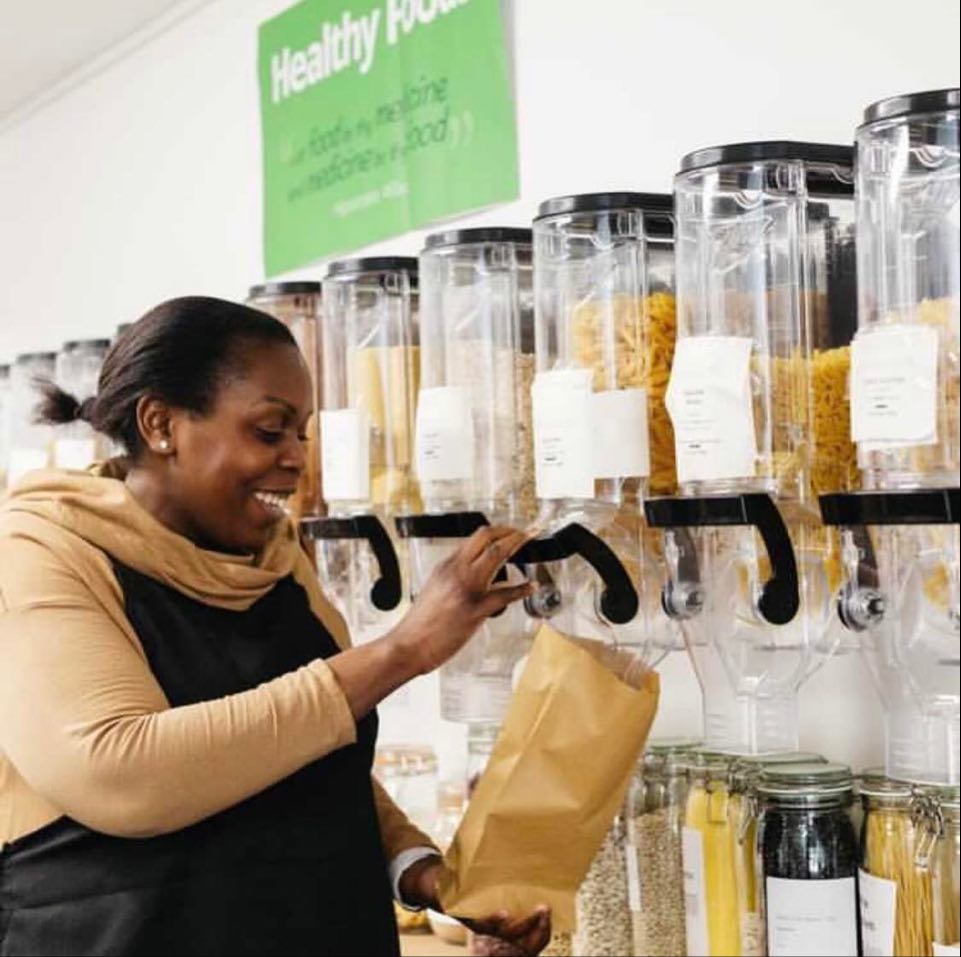 Bunmi from it's all about you eco refill store filling up a brown bag with pasta inside her shop