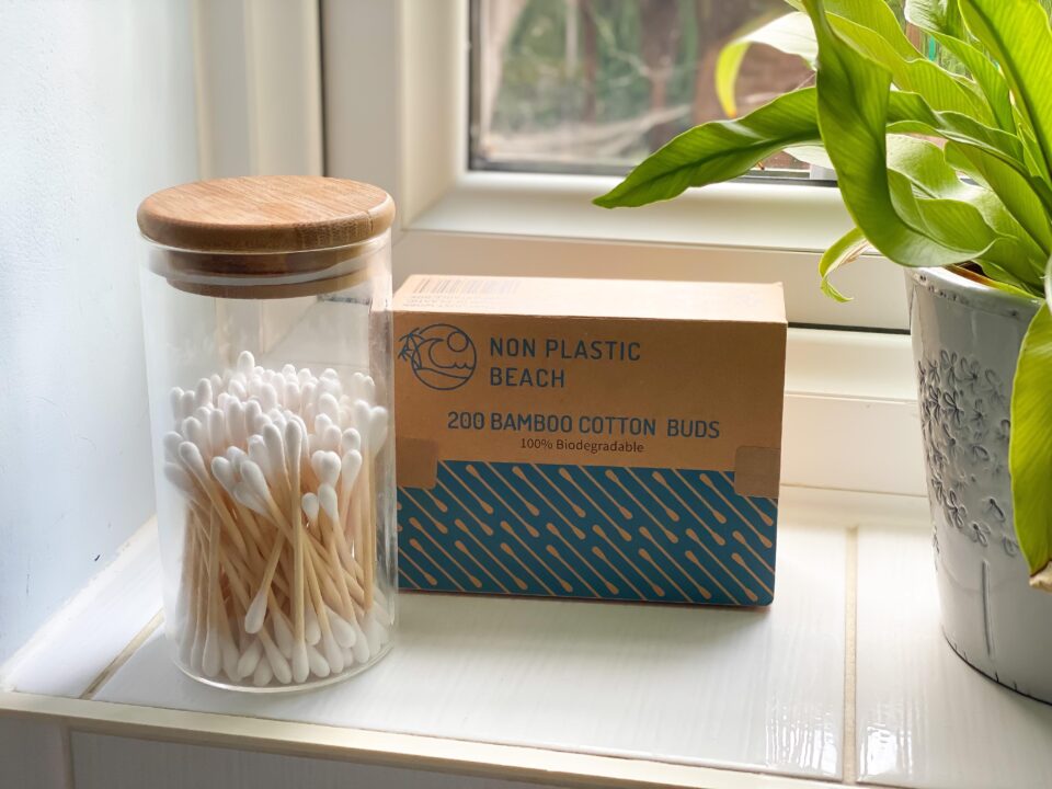 bamboo cotton buds on a window sill in a box with more in a reusable glass jar