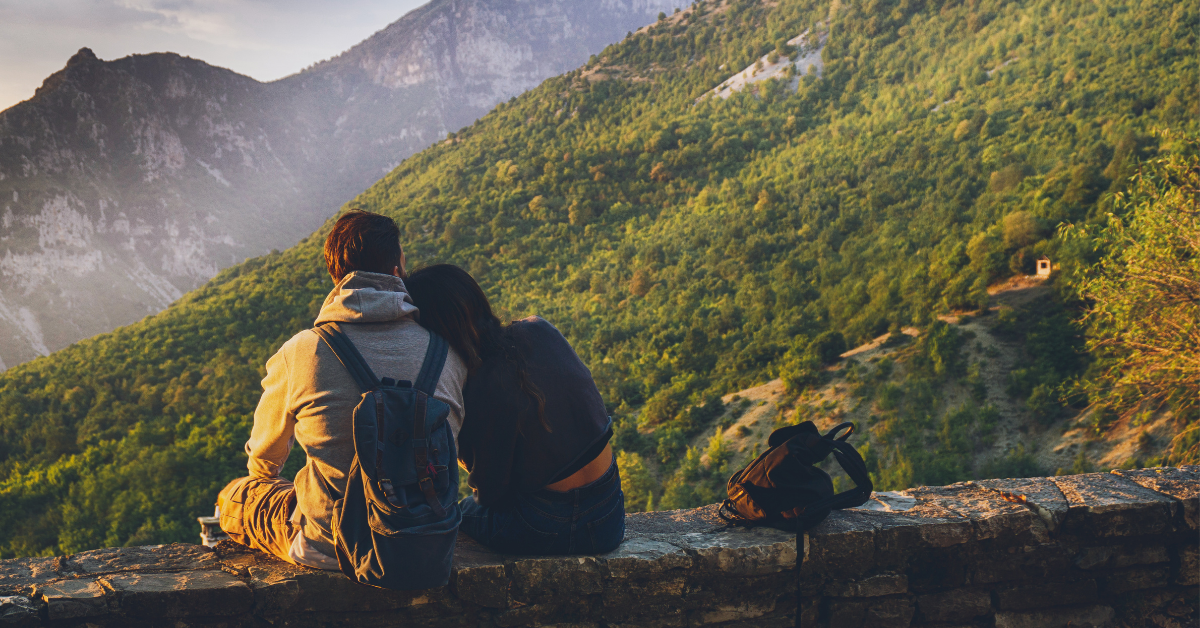 travel to mountains a couple sat on a wall