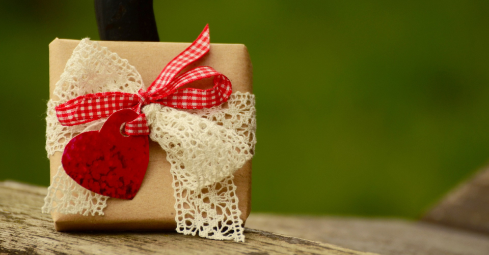 a small gift wrapped in brown paper with ribbons and a heart decoration