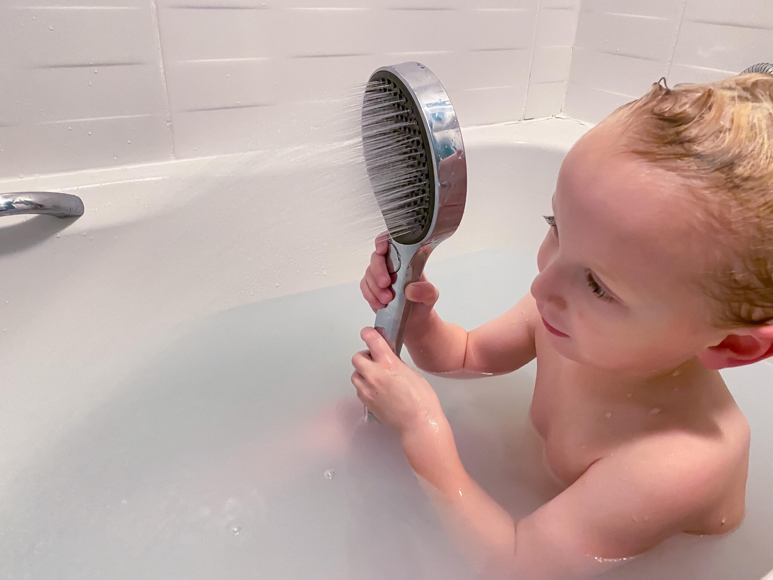 child holding the shower up using it himself