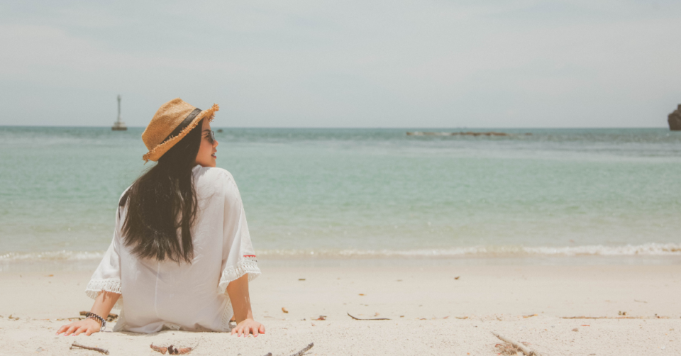 a lady sat on a lovely sandy beach looking to her right