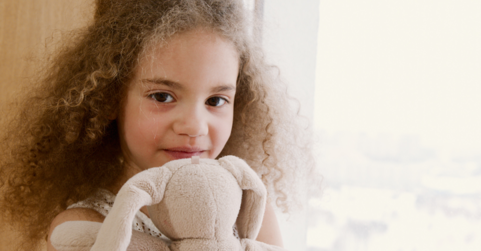 a child holding a soft toy rabbit