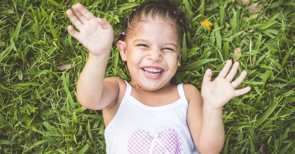 a child laying on grass and laughing