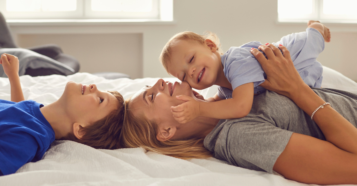 a mum wtith 2 kids laying a on bed