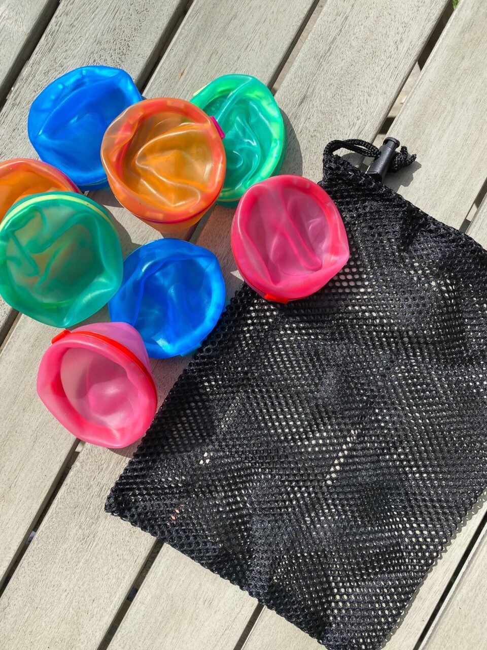 Soppycis reusable water balloons laid out on a table with the black drawstring bag