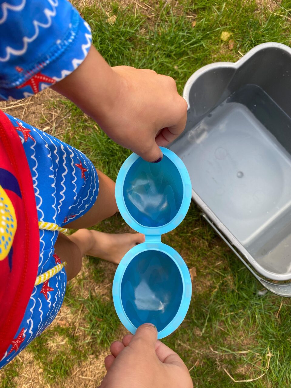 a child holding the reusable water balloon open to show the two sides