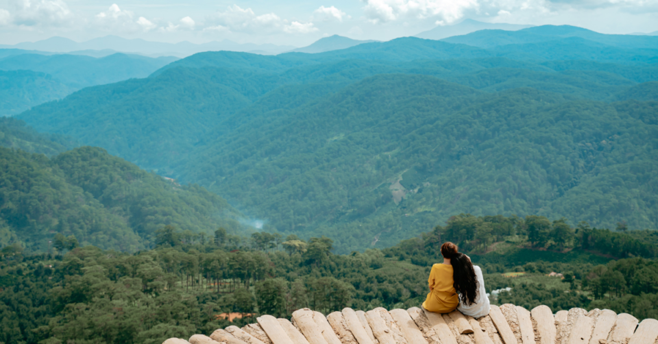two people sat looking across forests to show ecotourism is possible