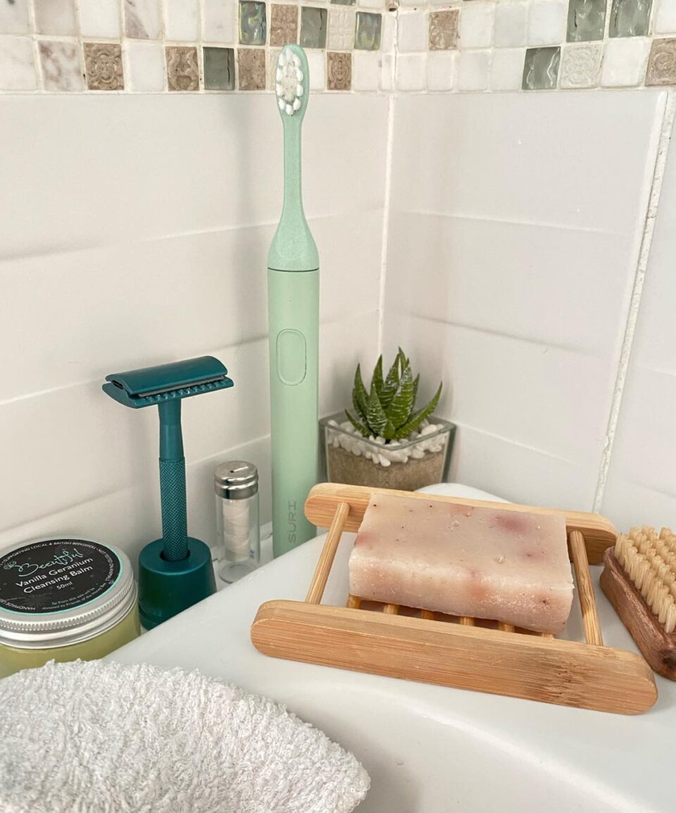 the SURI electric toothbrush on a sink with other eco products