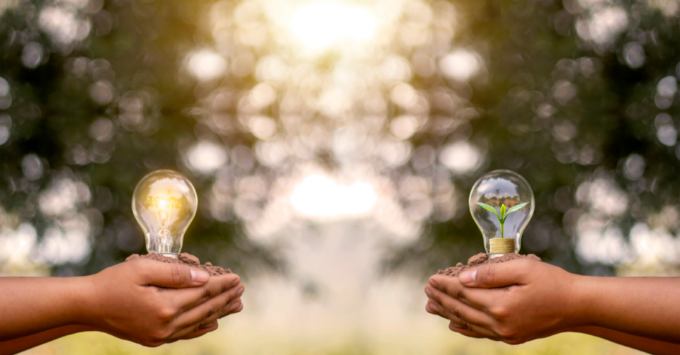 2 people holding light bulbs one showing energy saving