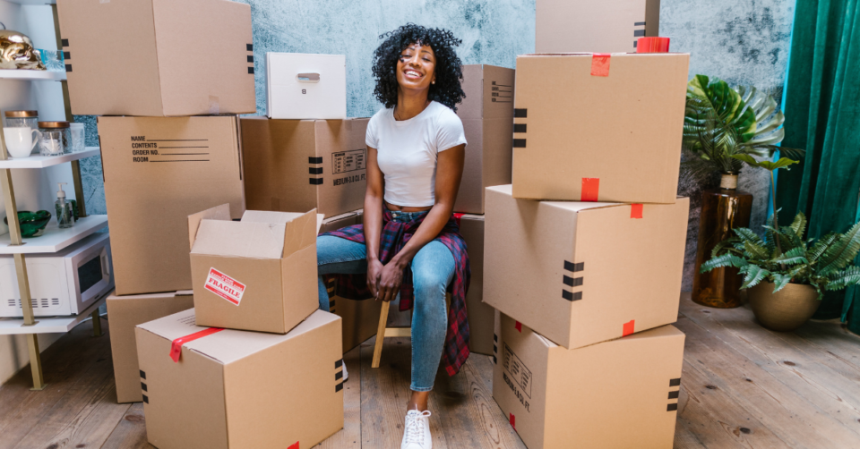 a lady sat with moving boxes all around her