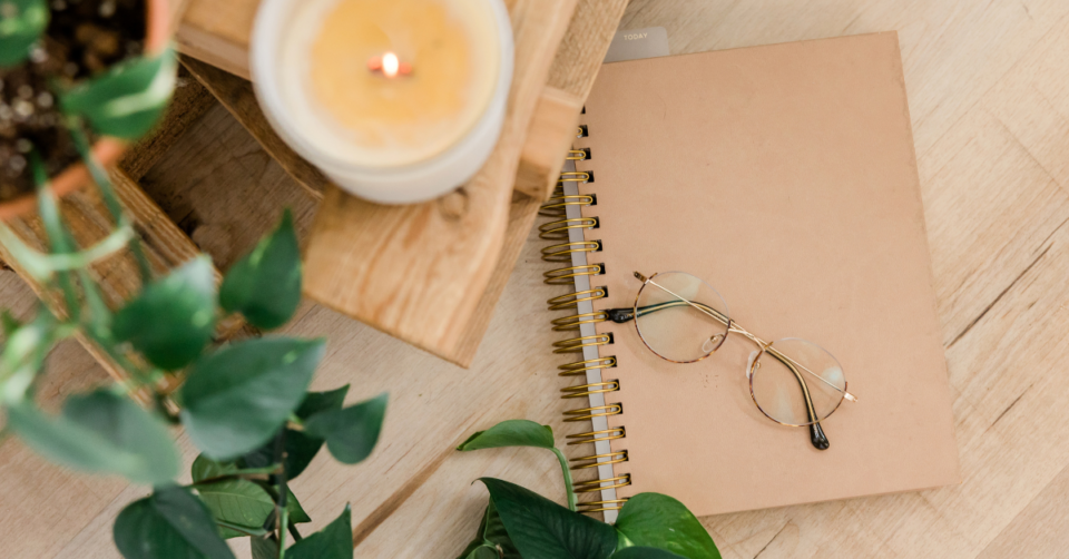 a plant, candle and notebook plus glasses