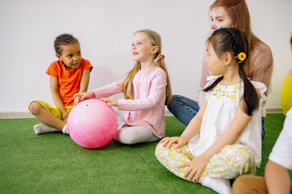 children sat in a circle holding a ball