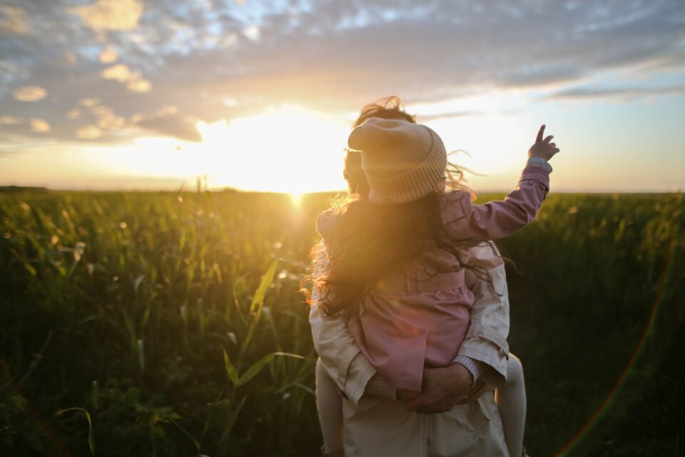 mum and child in a field at sunset