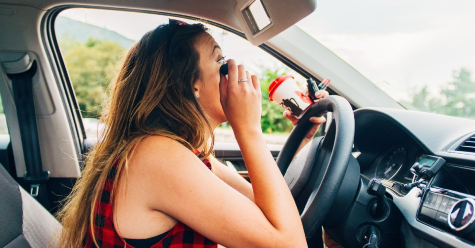 a lady putting on makeup in her car