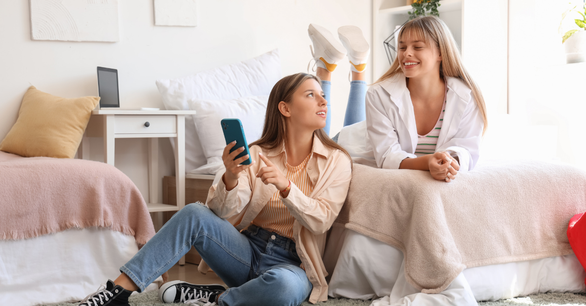 two students looking at their phone in their student bedroom