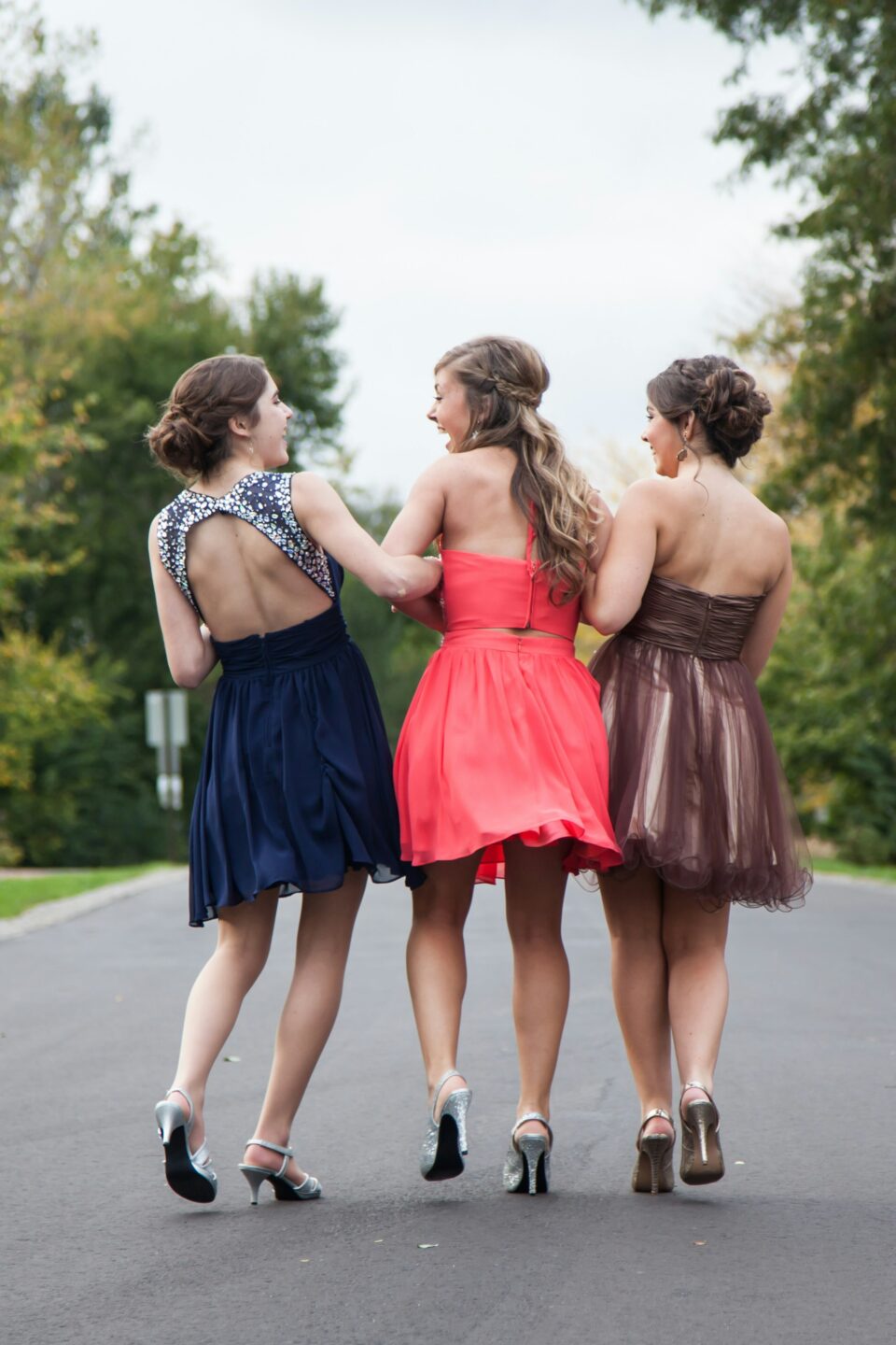 3 friends in prom dresses laughing 